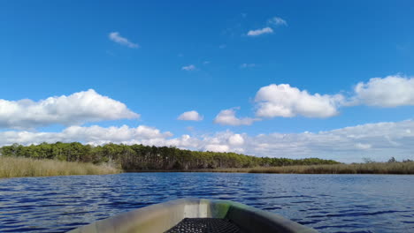POV-shot-of-a-kayak-in-a-salt-marsh-creek-with-blue-skies