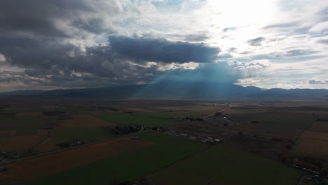 Drone-Aerial-shot-of-sunlight-coming-through-clouds-in-a-farm-field