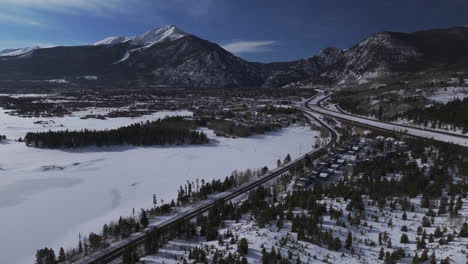 Downtown-Frisco-i70-Colorado-aerial-cinematic-drone-Lake-Dillon-Marina-Summit-cove-sun-cloudy-snowy-winter-morning-view-Silverthorne-Ten-Mile-Range-Breckenridge-calm-unfrozen-ice-forward-reveal