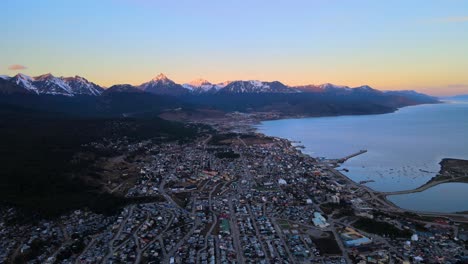 Drone-shot-flying-over-Ushuaia,-Argentina-at-sunset-towards-the-Andes-mountains