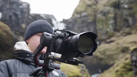 Male-videographer-hold-electronic-gimbal-with-camera-in-Icelandic-landscape