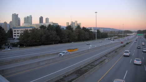 Verkehr-Auf-Mehrspuriger-Autobahn,-Hintergrund-Der-Skyline-Der-Stadt,-Statischer-Sonnenuntergang