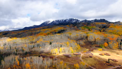 Dramatic-autumn-Aspen-Tree-fall-colors-Kebler-Pass-trailhead-aerial-cinematic-drone-snow-on-peaks-landscape-Crested-Butte-Gunnison-Colorado-early-fall-red-yellow-orange-Rocky-Mountains-upward-circle