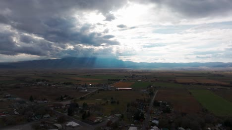 Drone-shot-of-rural-farm-land-after-a-storm-with-mountains-in-the-distance