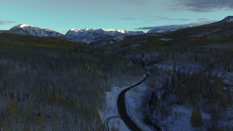 Frosted-road-crisp-cold-freezing-frozen-morning-shaded-Kebler-Pass-Colorado-aerial-cinematic-drone-shaded-fall-winter-season-collide-first-white-snow-red-yellow-orange-aspen-tree-forest-shaded-forward