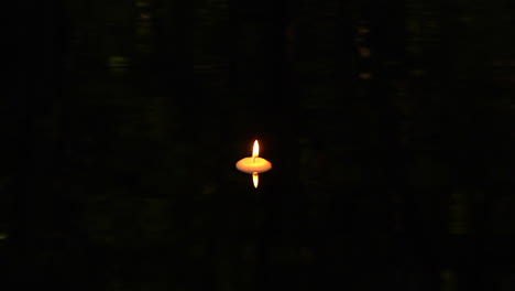 Floating-candle-in-dark-pool-of-water-with-reflection