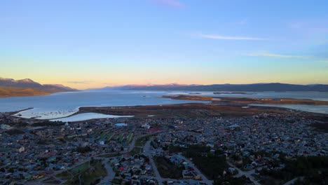 Drone-shot-flying-over-Ushuaia-at-sunset-towards-the-Beagle-Channel