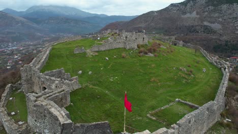Albanische-Burg-Von-Lezha:-Rote-Und-Schwarze-Flaggenwellen,-Umgeben-Von-Steinmauern,-Alte-Festung-Auf-Einem-Hügel