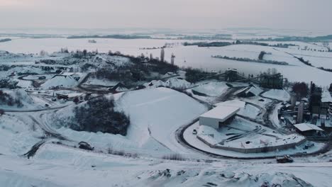 Flying-around-a-snowy-quarry-with-conveyor-belts-in-winter-evening