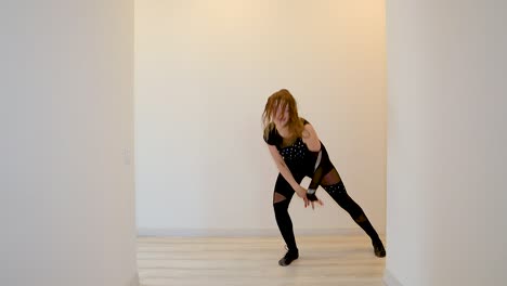Young-Caucasian-female-dancer-performing-a-dance-routine-in-slow-motion-wearing-a-black-outfit