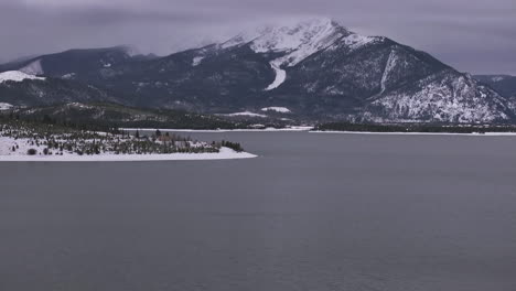 Lake-Dillon-calm-unfrozen-ice-downtown-Frisco-Colorado-aerial-cinematic-drone-cloudy-snowy-winter-morning-view-Breckenridge-Keystone-Silverthorne-Ten-Mile-Range-forward-reveal