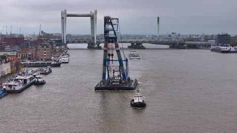 Boat-maneuvers-with-purpose,-guiding-industrial-crane-past-Dordrecht-waters