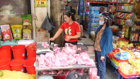 Wet-market-seller-cuts-and-weighs-meat-for-waiting-customer-at-busy-stall