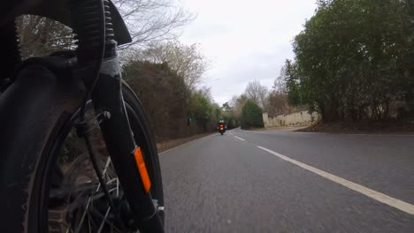 Low-angle-shot-following-a-motor-biker-on-a-country-lane