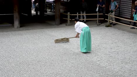 Worker-raking-gravel-in-slow-motion-at-Kasuga-Taisha-shrine-in-Nara-Japan