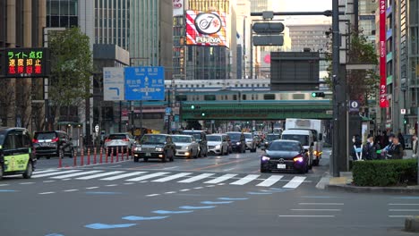 Vista-Dinámica-Dentro-Del-Centro-De-Tokio-Con-Tráfico-De-Automóviles-Y-Tren-Bala-En-Segundo-Plano.