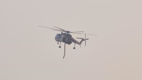 Helicóptero-Sobre-Un-Horizonte-Cubierto-En-Alberta,-Canadá,-Monitoreando-Un-Incendio-Forestal-Haciendo-Girar-Sus-Aletas