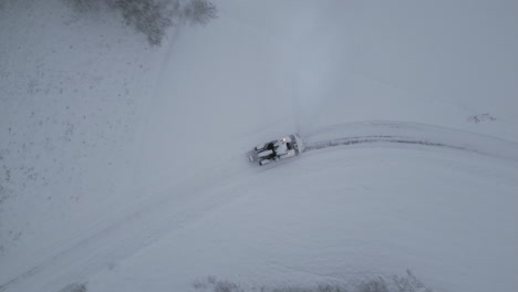Traktor-Pflügt-Schnee-Auf-Ländlicher-Landstraße-Im-Winter,-Aufsteigende-Luftaufnahme-Von-Oben-Nach-Unten