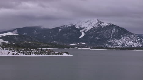 Lake-Dillon-Marina-Keystone-Summit-cove-Colorado-aerial-cinematic-drone-cloudy-snowy-winter-morning-view-Frisco-Breckenridge-Silverthorne-Ten-Mile-Range-peaceful-calm-unfrozen-ice-circle-left-motion