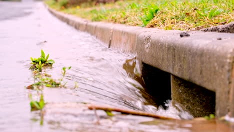 Rainwater-runoff-torrent-runs-down-concrete-gutter-into-stormwater-road-drain