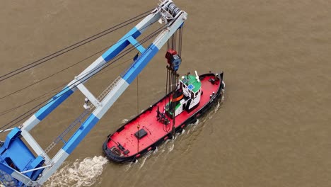 Tug-boat-towing-industrial-crane-platform-on-river-with-sense-of-purpose