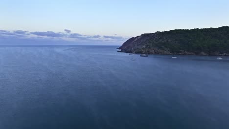 Meeresnebel-Steigt-In-Mystischen-Ranken-über-Booten-Auf,-Die-Am-Unberührten-Strand-Von-La-Vall-Menorca-Vor-Anker-Liegen