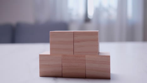 Taking-a-close-up-shot-of-an-individual-stacking-wooden-blocks-on-top-of-each-other-on-a-table