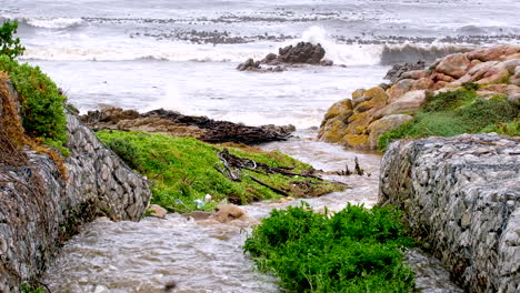 Telephoto-view-of-rainwater-runoff-channeled-by-gabion-walls-toward-ocean