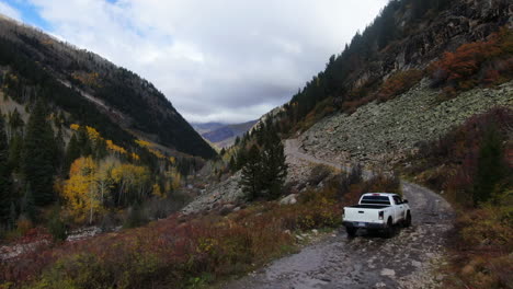 Cinematic-drone-aerial-4wd-truck-off-road-Marble-Crystal-Mill-stunning-autumn-Aspen-fall-colors-Southern-Colorado-Rocky-Mountains-peaks-Ouray-Telluride-camping-by-river-yellow-trees-slowly-up-forward
