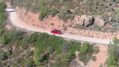 Red-car-driving-on-dirt-road-in-Grevalosa-mountains