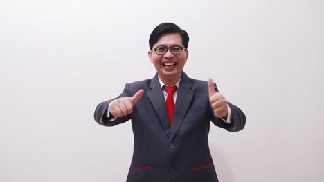 Excited-asian-businessman-standing-while-showing-thumbs-up