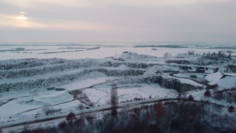 Flying-towards-a-snowy-quarry-in-Bohemia-with-an-incoming-car-in-winter-evening
