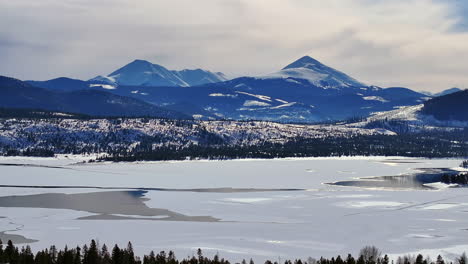 Downtown-Frisco-toward-Breckenridge-Colorado-aerial-cinematic-drone-Lake-Dillon-Marina-Keystone-Summit-cove-cloudy-snowy-winter-morning-view-Silverthorne-Ten-Mile-Range-calm-unfrozen-ice-upwards