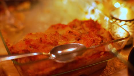 Patatoe-gratin-with-crispy-cheese-layer-in-a-dish-on-a-table-with-candles
