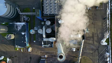Aerial-view-above-a-smoking-factory-chimney,-sunny-day---top-down,-drone-shot