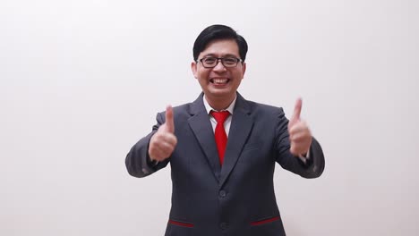 Asian-businessman-standing-while-presenting-both-sides-and-showing-thumbs-up-and-fist-hands