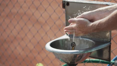 Slow-motion-closeup-of-man-washing-hands-in-stainless-steel-sink-with-water-spurting-from-spigot