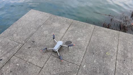Drone-on-a-ground-ready-for-take-off,-flying-near-water