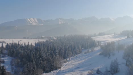 Fairy-tale-village-by-majestic-Tatra-mountains,-Poland-on-sunny-winter-day,-aerial-day