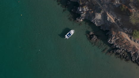 Top-down-aerial-shot-over-a-small-stationary-boat-in-clear-water
