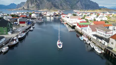 Boat-Sails-in-Henningsvaer-Harbour,-Lofoten-Island,-Norway,-Scandinavia---4k-Aerial-Reveal