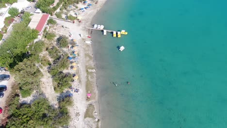 Drone-view-in-Greece-flying-over-a-light-and-dark-blue-lake-with-small-boats-and-surrounded-by-green-landscape-on-a-sunny-day-in-Crete
