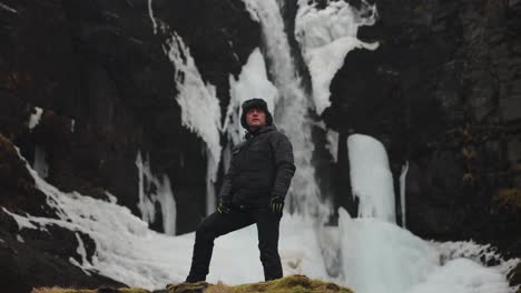 Tourist-stand-near-Icelandic-waterfall-and-dark-volcanic-rugged-cliff