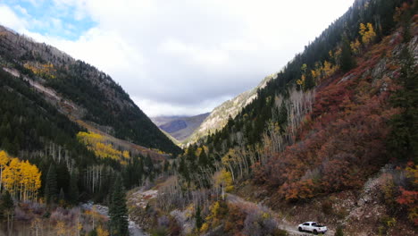 Cinematic-drone-aerial-4wd-truck-off-road-Marble-Crystal-Mill-stunning-autumn-Aspen-fall-colors-Southern-Colorado-Rocky-Mountains-peaks-Ouray-Telluride-camping-by-river-yellow-trees-downward-motion