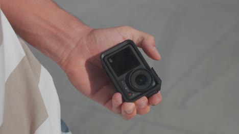 Person-remove-small-action-camera-in-black-color-from-pocket-and-hold-in-hand