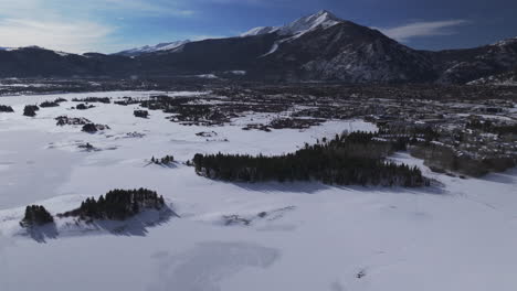 Snowy-Downtown-Frisco-i70-Colorado-aerial-cinematic-drone-Lake-Dillon-Marina-Summit-cove-sun-cloudy-winter-morning-view-Silverthorne-Ten-Mile-Range-Breckenridge-calm-frozen-ice-forward-reveal