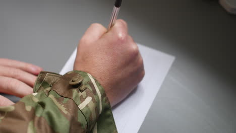 Un-Soldado-Del-Ejército-Marino-Escribiendo-Una-Carta-En-Un-Trozo-De-Papel-Con-Un-Bolígrafo.