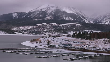 Lake-Dillon-Marina-Keystone-Summit-cove-Colorado-aerial-cinematic-drone-cloudy-snowy-winter-morning-view-Frisco-Breckenridge-Silverthorne-Ten-Mile-Range-peaceful-calm-unfrozen-ice-backward-motion