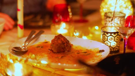 Leftover-of-lamb-meat-on-a-plate-in-between-candles-during-party