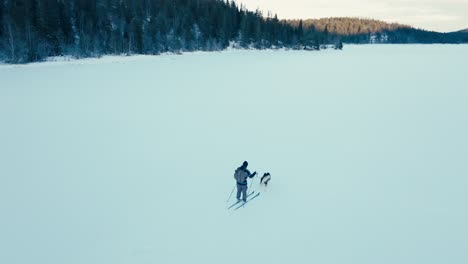Esquiar-Con-Perro-En-Un-Lago-Congelado-A-Lo-Largo-De-Las-Montañas-En-Indre-Fosen,-Noruega